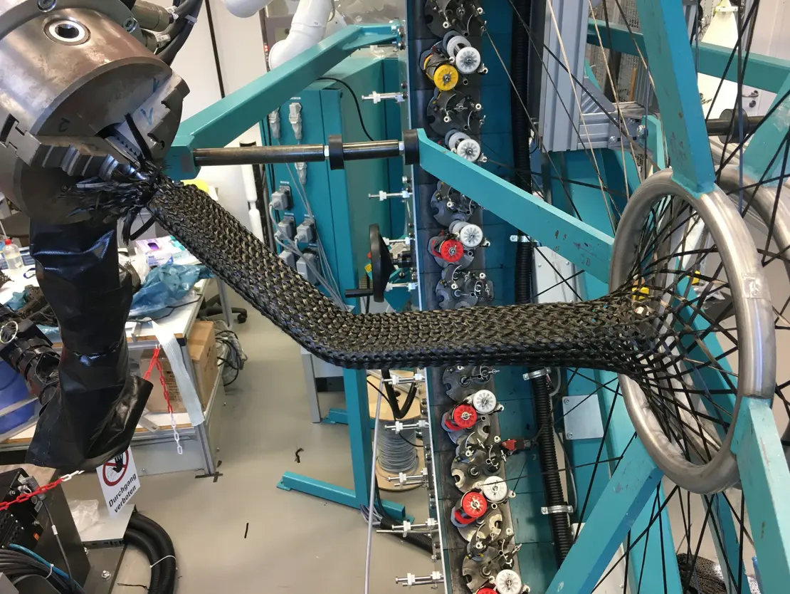 FVK-Bauteile mit komplexen Geometrien? Automatisieren Sie die Fertigung! Stehfäden machen biaxiales zum triaxialen Bauteilgeflecht und schmiegen es an den Kern.